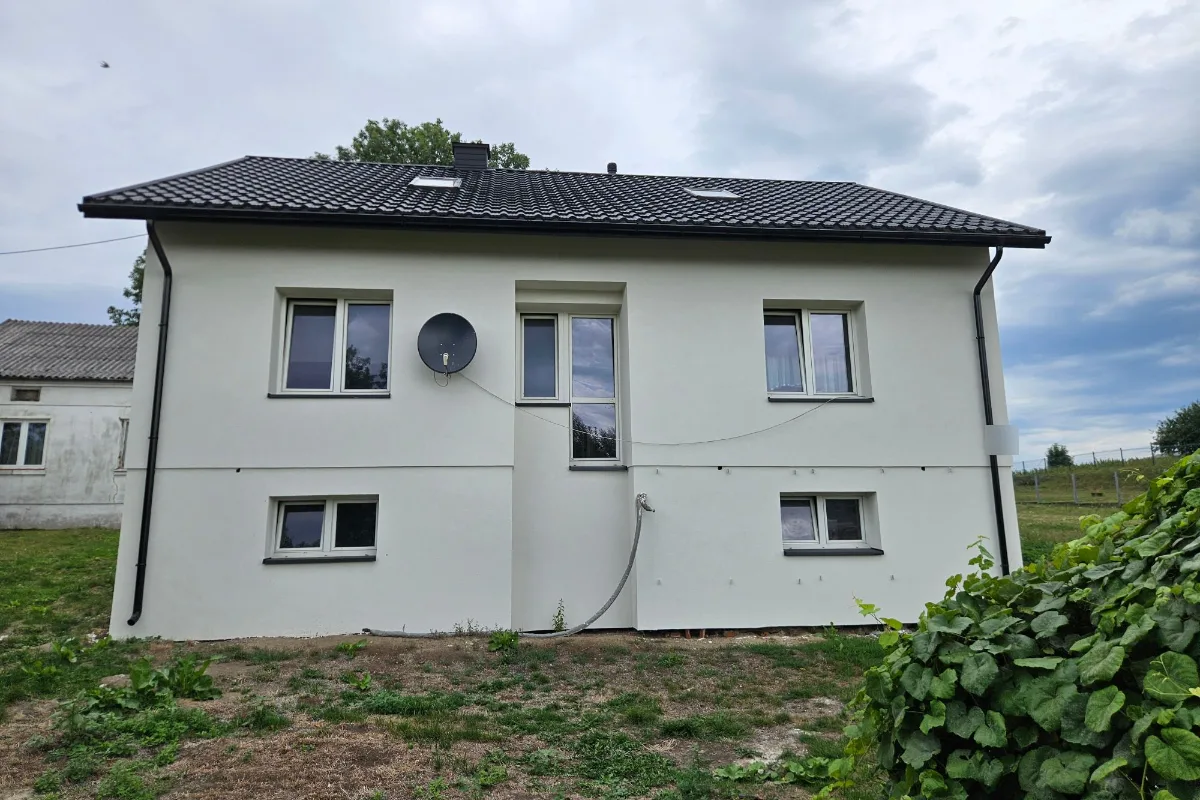 Dom z cegły po dociepleniu: gładka, biała elewacja frontowa